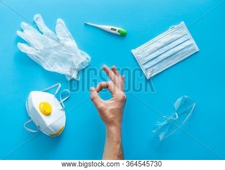 Mans Hand Showing Ok Sign With A Medical Protective Mask, Respirator Ffp, Rubber Gloves, Thermometer