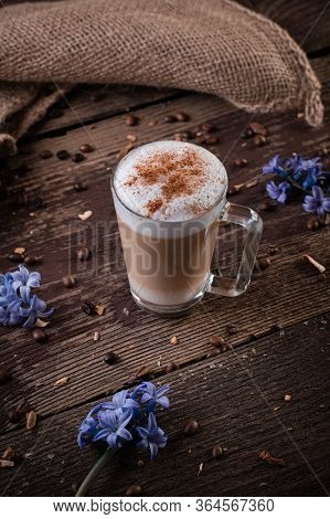A Glass With Latte Macchiato On Wooden Background With Blue Flowers