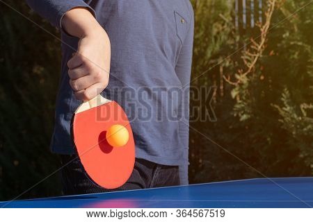 A Boy Playing Table Tennis, Ping Pong Outside In The Garden.
