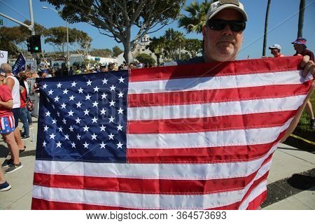 Laguna Beach, California / USA - May 2, 2020. #OpenUpCa. Various people smile, hold signs, flags, wave and cheer as they protest the Coronavirus Lock Down in Laguna Beach, California. 
