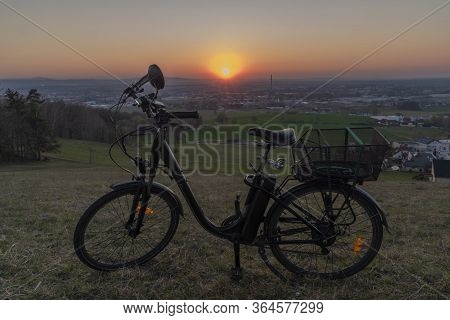 Black Electric Bike On Ski Slope In Budweis City With Sunset