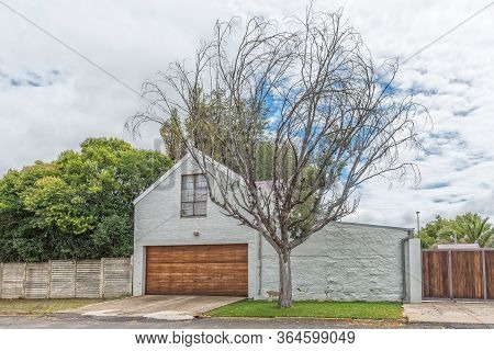 Harrismith, South Africa - March 16, 2020:  A Street Scene, With A Garage And Dead Tree, In Harrismi