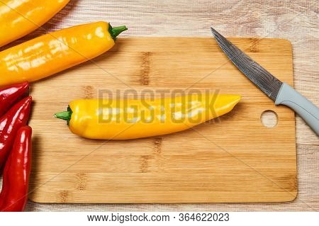 Still Life With Yellow And Red Pods Of Sweet Pepper And Kitchen Knife On A Cutting Board