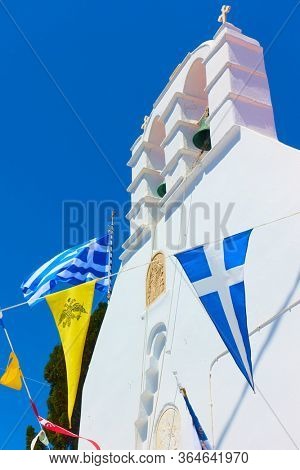 Greek othodox church drcorated by flags in celebration, Mykonos island, Greece