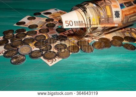 Many Eruos Banknotes And Coins Inside Glass Jar On Table