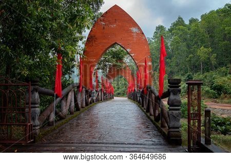 Bridge With Archs And Red Flags In The Entrance To My Son Sanctuary In Central Vietnam