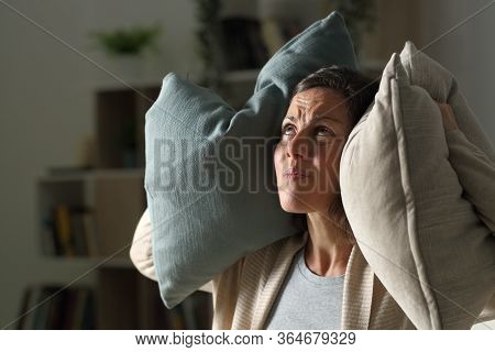 Annoyed Adult Woman Suffering Neighbour Noise In The Livingroom At Night At Home
