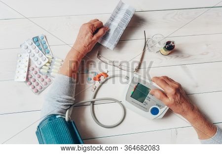 Senior Wrinkled Hand Pushing Back Pills And Thermometer, Dumb-bell On A Table. Another Old Woman Han