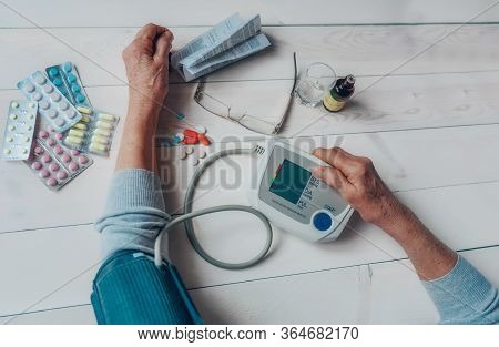 Senior Wrinkled Hands With Blood Pressure Measure Cuff, Medicine Bottle, Glass, Colorful Pills, Ther