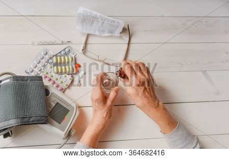 Senior Wrinkled Hands With Blood Pressure Measure Cuff, Medicine Bottle, Glass, Colorful Pills, Ther
