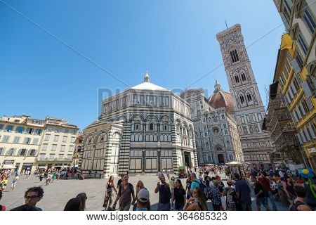 Florence, Italy - August 1, 2019: Tourists enjoy the view of Florence Baptistery at piazza San Giovanni at sunny summer day