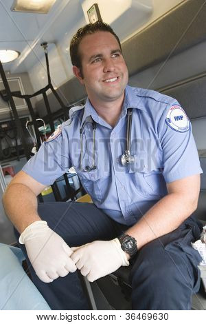 Happy EMT doctor sitting in ambulance and looking away