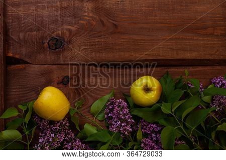 Bright Yellow Apples, Purple Lilac Flowers With Fresh Green Leaves On Wooden Background Flat Lay.col