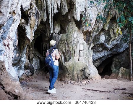 Back View Of Asian Woman Tourist Walking Into The Cave. Hipster Backpacker Journey Lifester.
