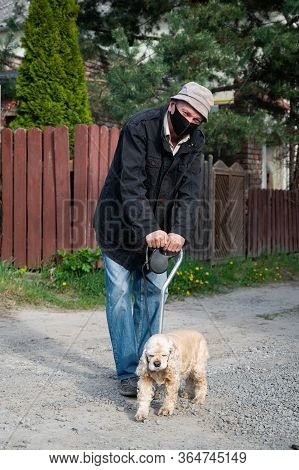 Senior Man In Protective Mask With A Cane Walking With A Dog In Sunny Day