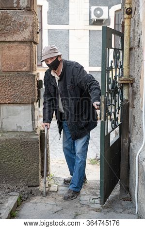 Senior Man In Protective Mask With A Cane Posing Near Gate Outdoors