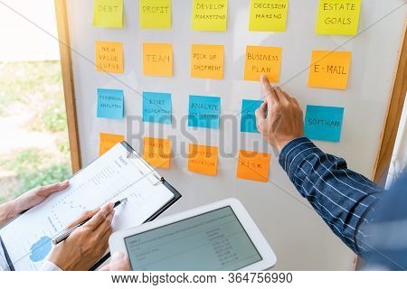 Young Business Workers Posting With Sticky Notes Stickers Reminders  Creative Brainstorming At Board