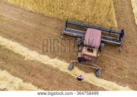 Tractor With A Reaper On The Edge Of A Wheat Field Close-up. Next To The Tractor Is An Agronomist. T