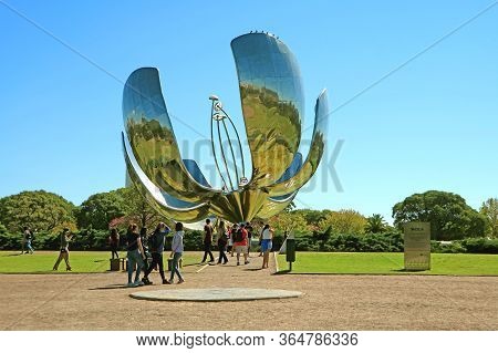 Group Of Visitors Impressed By The Floralis Generica, A Flower Sculpture Made Of Steel And Aluminum,