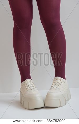 Long Slender Legs Close-up. Thick-soled Sneakers. Red Stockings Or Tights. Trend, Fashion, Trend