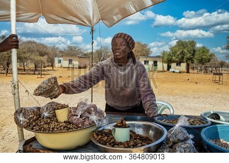 elderly African woman selling peanuts and beans in the street  in her village, rural area
