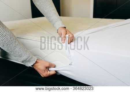 closeup of a young caucasian man covering a mattress with a white mattress protector