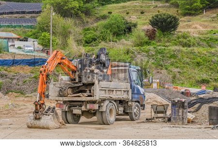 Daejeon, South Korea; May 3, 2020: Backhoe Loaded Into Back Of Truck At Rural Construction Site.