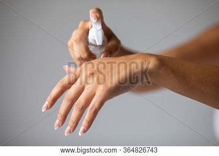 Close up view of woman person using small portable antibacterial hand sanitizer on hands. Stock photo