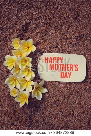 Happy Mothers Day Wish Written On White Paper Note With Plumeria Flowers On Sand