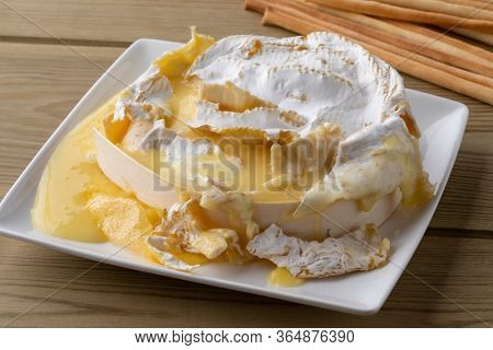 French Camember fondue close up with bread sticks on a wooden table 