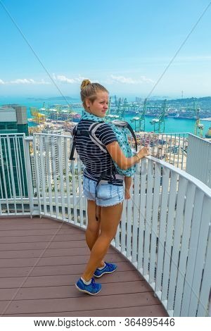 Sexy Young Woman In Short Shorts With Infant In Baby Ergo Carrier Looking At Beautiful Singapore Roo
