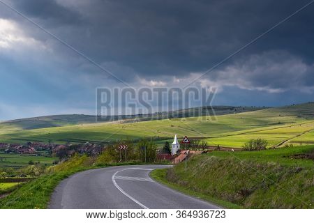 Asphalt Road Leading To A Small Typical  Hungarian Transylvanian Village At Springtime, Gathering St