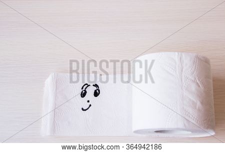 Toilet Paper With Funny Smiling Face On Wooden Background, Copyspace. Supplies For Quarantine Isolat