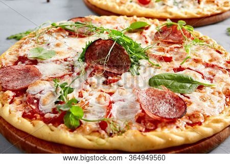 Prosciutto Funghi pizza on wooden board. Traditional italian cuisine bakery with salami, champignons, bell pepper, tomatoes, mozzarella and red tomato sauce close up. Hot snack, pizzeria meal