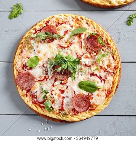 Prosciutto Funghi pizza on wooden board. Traditional italian cuisine bakery with salami, champignons, bell pepper, tomatoes, mozzarella and red tomato sauce close up. Hot snack, pizzeria meal