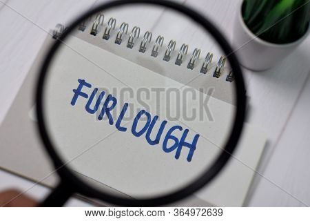 Furlough Write On Sticky Notes With Magnifying Glass Isolated On Office Desk