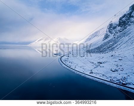 Aerial view of the icelandic coastline with road along the ocean and snowcapped mountains in the back, Eastfjords, Iceland, Europe