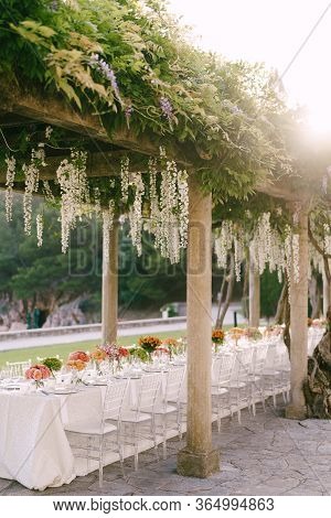 Wedding Dinner Table Reception. A Very Long Table For Guests With A White Tablecloth, Floral Arrange