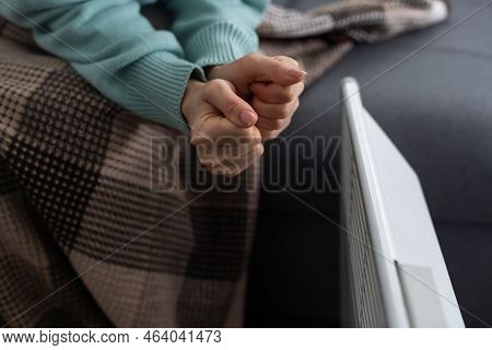 Girl Warms Up The Frozen Hands Above Hot Radiator, Close Up. Woman Wearing Woolen Sweater Warming Up