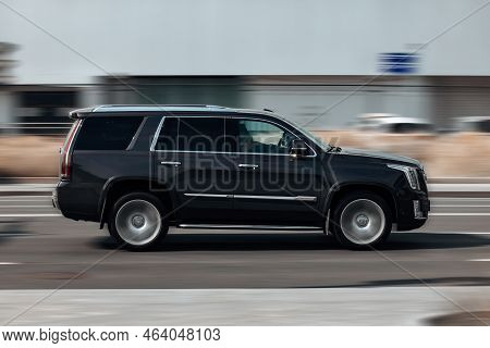 Fast Moving Cadillac Escalade On The City Road. Black Suv With Man Driving. Premium Auto In Fast Mot