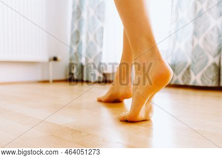 Woman Walks Barefoot On Light Parquet Floor Near Large Window, Heating Radiator, Close-up. Walking B