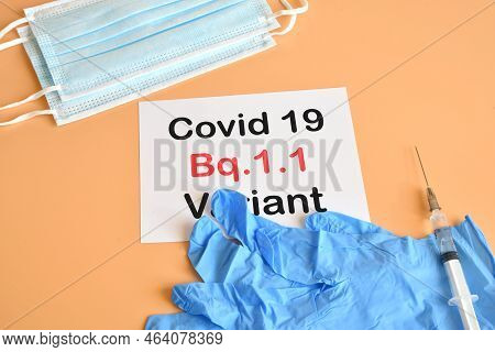 Protection Masks, Blue Surgical Gloves And Vaccine Syringe With White Paper And Text Covid 19 Bq.1.1