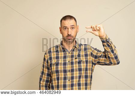 Unhappy Latin Bearded Man Looking Disappointed And Showing Small Gesture, Small Amount Or Downscale 