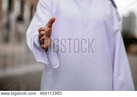 A Man In Traditional Arabian Strecthing His Hand For A Handshake