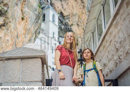 Mother And Son Tourists In Monastery Of Ostrog, Serbian Orthodox Church Situated Against A Vertical 