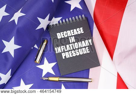 Business Concept. On The American Flag Lies A Pen And A Notebook With The Inscription - Decrease In 