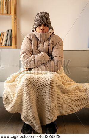 Unhappy Man Feeling Cold Wearing Warm Winter Clothes Indoors. Sad Broke Poor Person No To Pay Electr