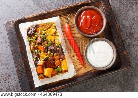 Turkish Kebab With Potatoes, Green Peas, Onions And Carrots Wrapped In Paper And Baked Close-up On A
