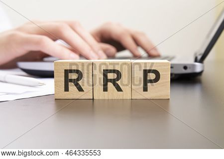 Rrp - Acronym From Wooden Blocks With Letters. Background Hands On A Laptop With Blur