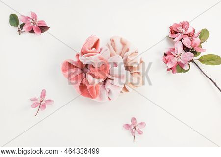 Three Trendy Pink Velvet Scrunchies And Fresh Spring Red Flowers On Whitel Background. Flat Lay, Top